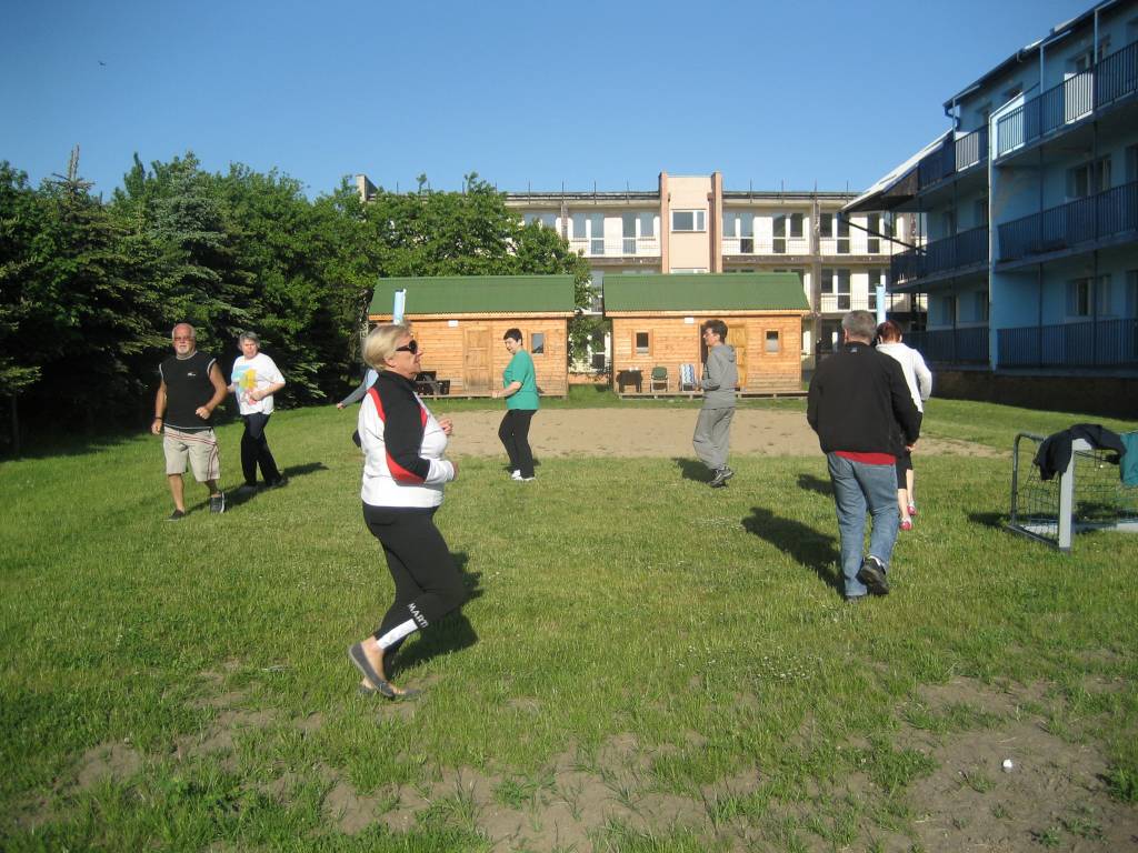 Turnus Rehabilitacyjny Sarbinowo 2012 r. Uczestnicy wyjazdu ćwiczą na boisku przed budynkiem sanatorium.